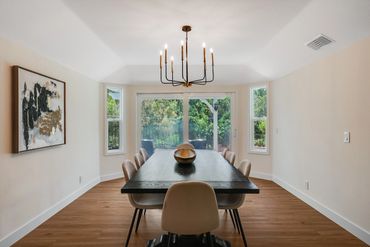 Modern dining room with black table, beige chairs, and large windows.