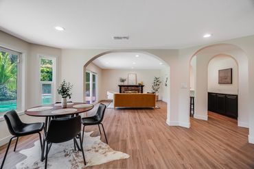Modern dining and living room with wood flooring and large windows.