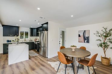 Modern kitchen and dining area with navy cabinets and brown chairs.