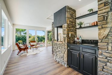 Bright living area with stone bar and cozy seating by large windows.