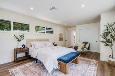 Bright modern bedroom with a cozy bed and blue velvet bench.