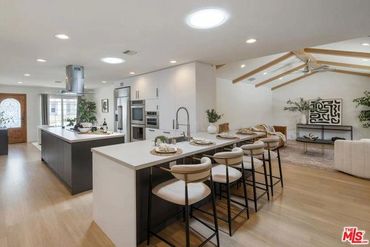 Modern open kitchen with island, bar stools, and vaulted ceiling living area.
