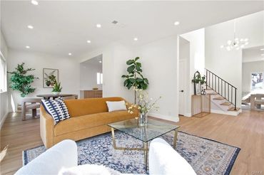 Bright living room with mustard sofa, glass coffee table, and patterned rug.