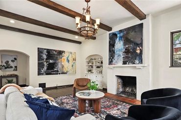 Cozy living room with modern art, wooden beams, and a fireplace.