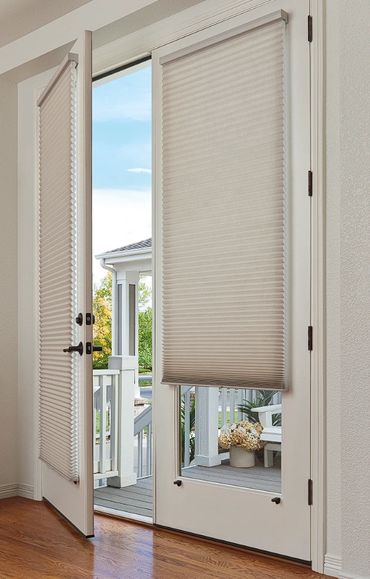 White French doors with beige pleated blinds partially open to a porch with plants.