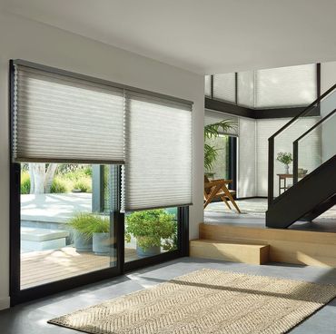 Modern living room with large windows and light-filtering blinds.