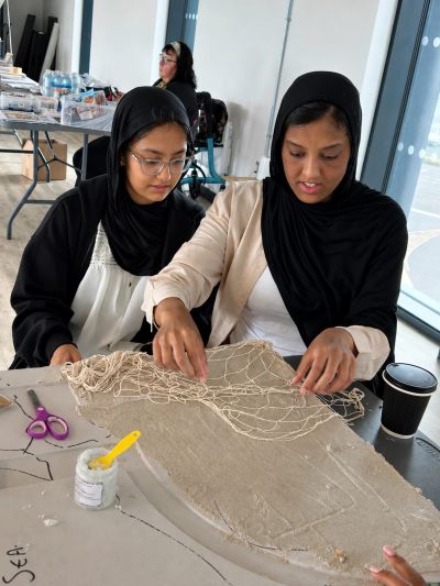 Two women working on a net or textile project.