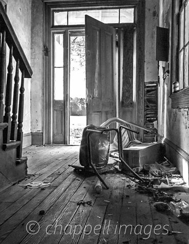 Inside, an open door revels debris cluttering an old farm house. Old House NC