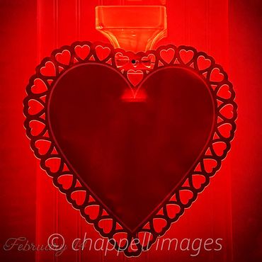 Deep red heart-shaped lamp illuminated in red.