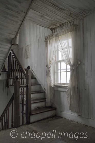 landing between sets of stairs. Light filters in from window illuminating shabby curtains. Edenton