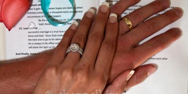 Bride and Groom's hands with wedding bands and rose.