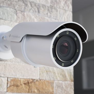 Close-up of a white security camera mounted on a stone wall.