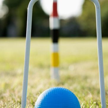 Ball going through croquet hoop and the centre peg in the background