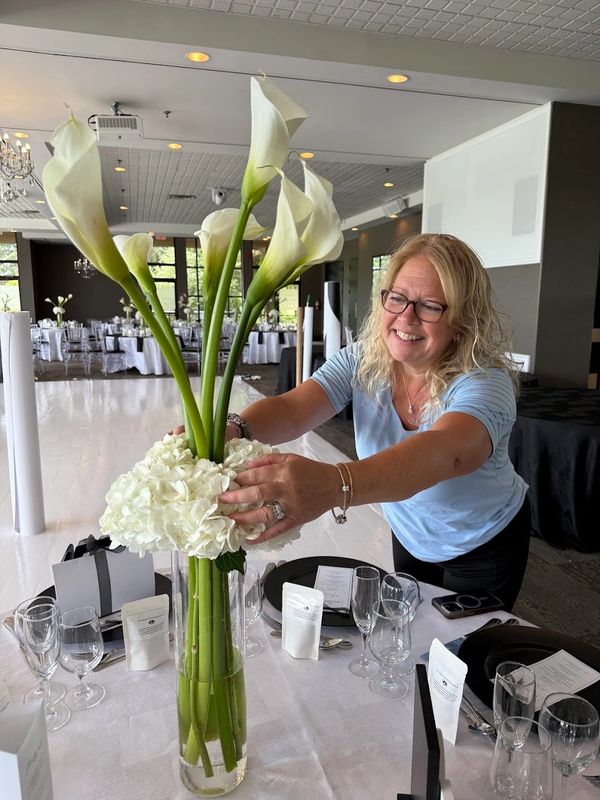 Woman arranging tall white flowers in a vase.