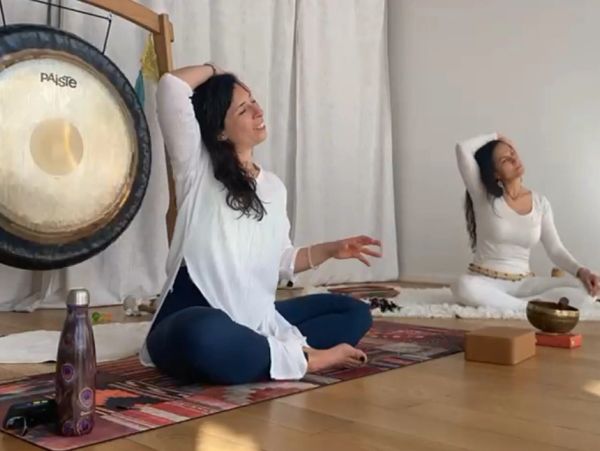 Deux femmes pratiquent des étirements pendant une séance de méditation.