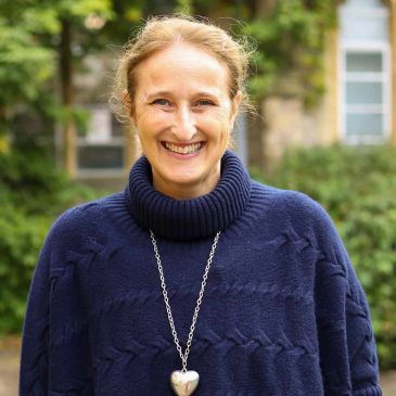 Smiling woman in a blue sweater outdoors.