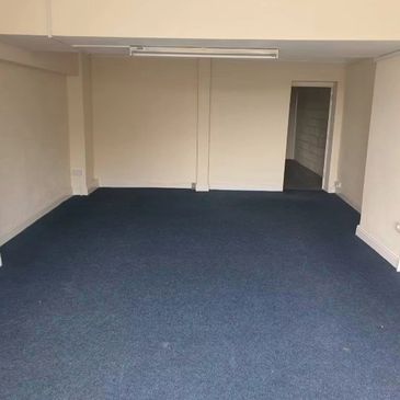 Empty room with blue carpet and beige walls.