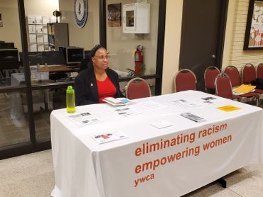 Woman sitting behind a YWCA informational table.