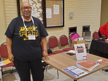 Man at outreach program table with materials and brochures.