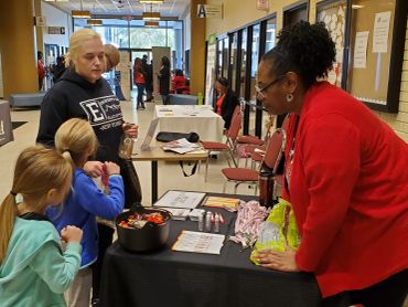People interacting at a school or event info table.