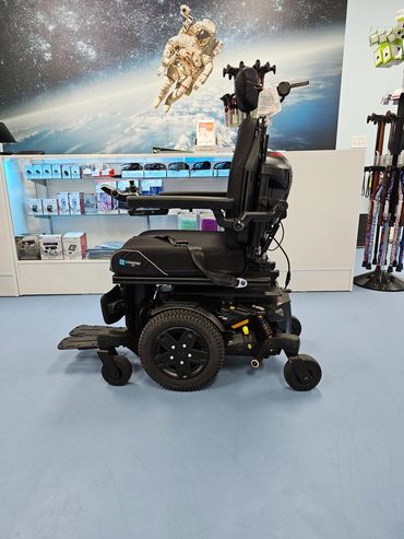 Black electric wheelchair displayed indoors with space-themed wall art.