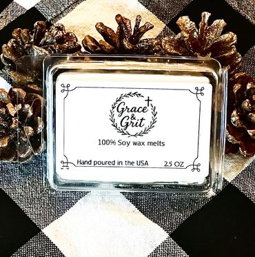 Grace & Grit soy wax melts with pinecone decoration on checkered cloth.