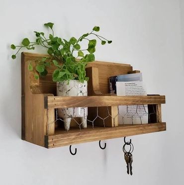 Rustic wooden wall shelf with plant, books, and hanging keys.