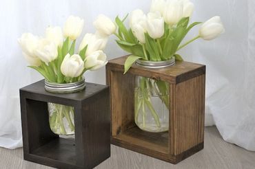 Two wooden box frames holding jars with white tulips inside.