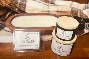 Set of Cozy Flannel soy wax candles and melts with wooden lids on a wooden table.