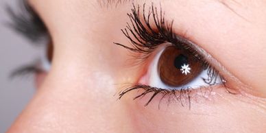 A close up picture of a brown eyed girl with long eyelashes looking up and away from the camera