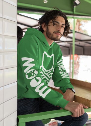 Man wearing a green hoodie with white graphics sitting at a counter.