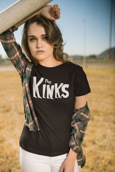 Woman in a black The Kinks t-shirt and plaid shirt outdoors.