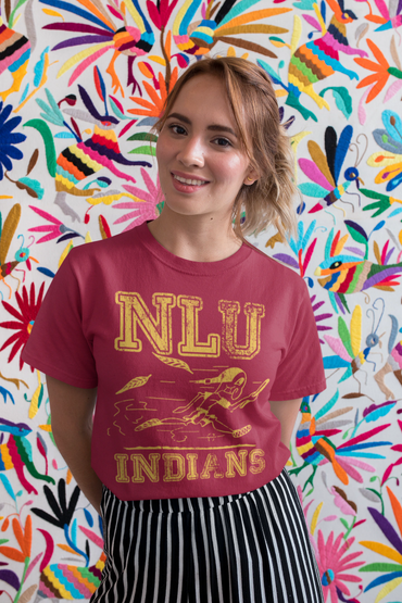 Smiling woman in a red NLU Indians t-shirt stands against a vibrant embroidered wall.