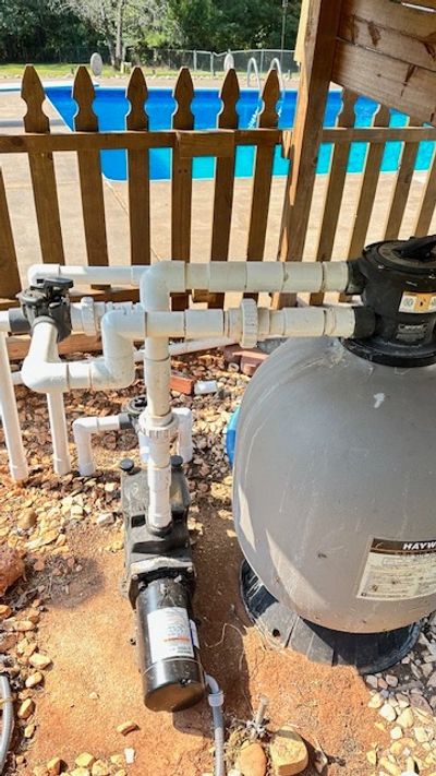 Pool pump and filtration system next to a fenced pool area.