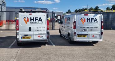 Two white HFA Electrical Ltd vans parked side by side under a clear sky.