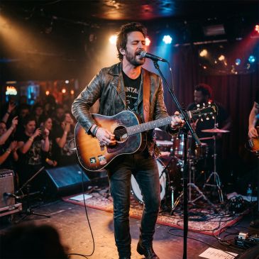 Man singing and playing guitar on stage.