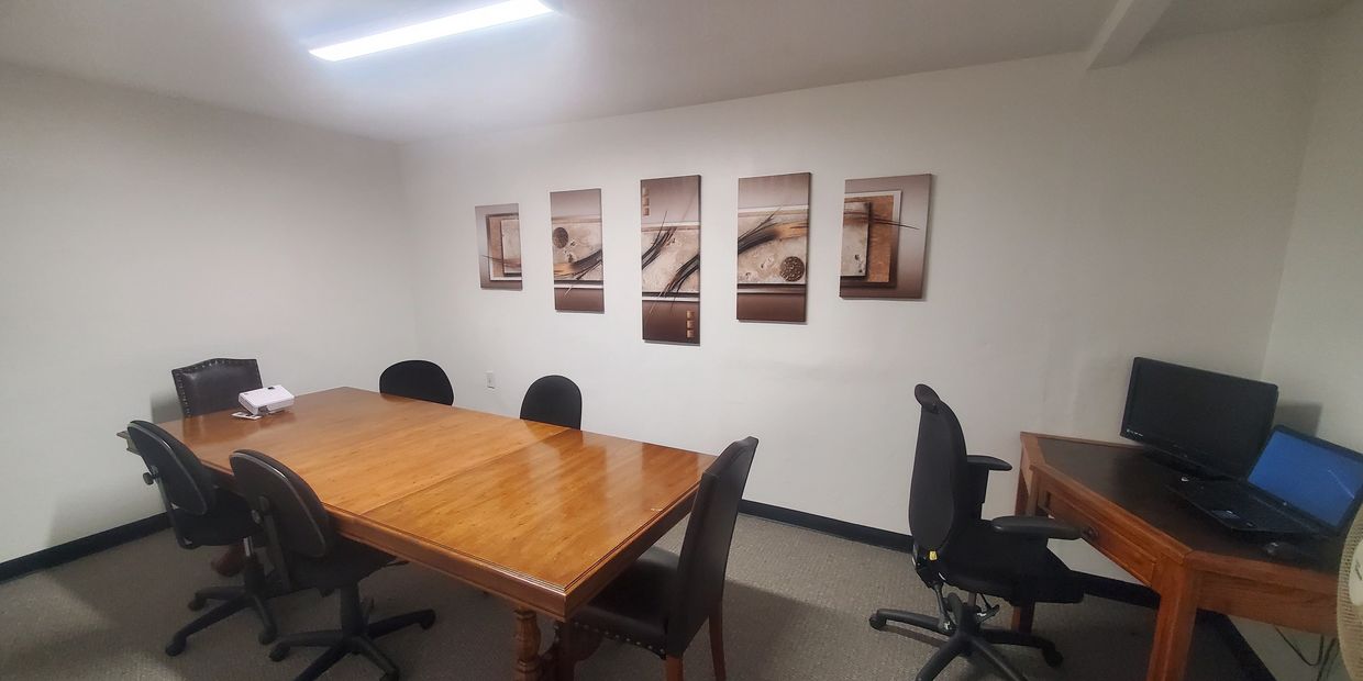 A small conference room with a wooden table, black chairs, and abstract wall art.