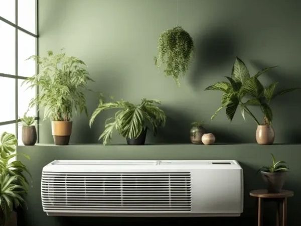 Modern white air conditioner with green plants on a green wall background.