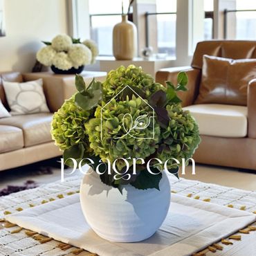 Green hydrangea bouquet in a white vase on a table in a cozy living room.