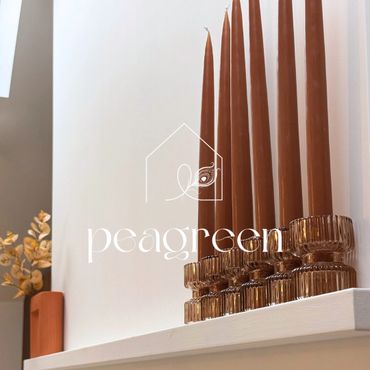 Brown taper candles in ribbed glass holders on a white shelf with dried flowers in the background.