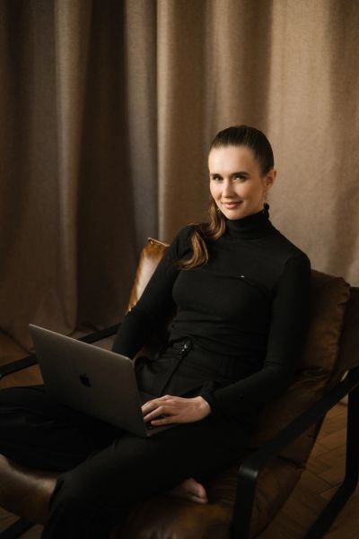 Woman working on a laptop while sitting in a leather chair.