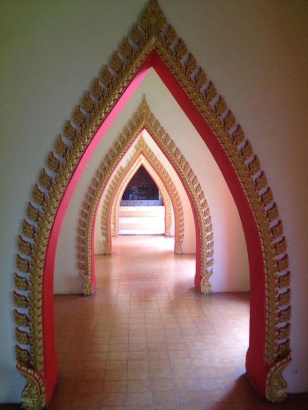 A series of ornate, golden-trimmed arches creating a hallway with a tiled floor.