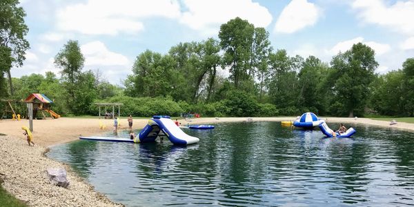 Swimming pond with raft and inflatable. Sandy beach with playground for the kids. 