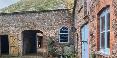 Stone courtyard with arched windows and blue doors in rustic buildings.