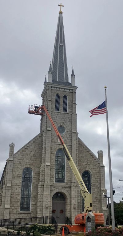 Church steeple maintenance with American flag.