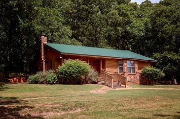 Cozy cabin with a green roof in a wooded area.