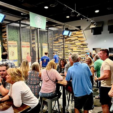 A corporate team enjoying a team-building axe throwing session in a private arena.