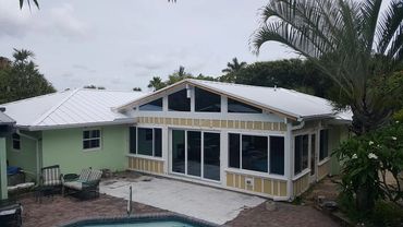House exterior with a pool, patio furniture, and ongoing renovation work.