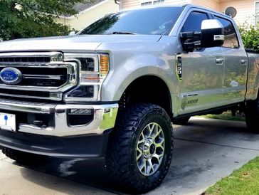 A silver Ford F250 pickup truck with a lift kit.