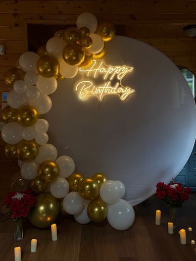 Elegant birthday setup with gold and white balloons.